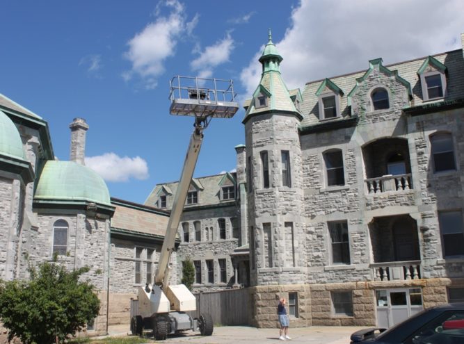 Aerial lift positioned at a stone institutional building